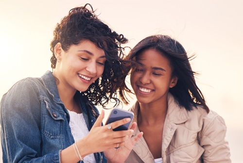 deux femmes rigolent sur leur smartphone