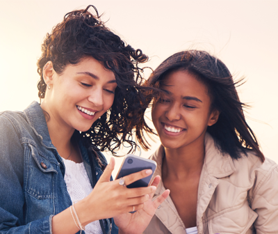 deux femmes rigolent sur leur smartphone