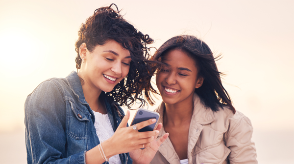 deux femmes rigolent sur leur smartphone