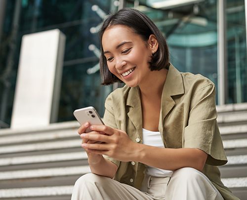 Technology and communication. Young smiling girl, asian woman sits with smartphone, reads message with big smile