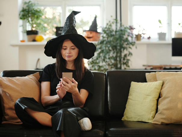 Une femme déguisée pour Halloween recevant un SMS sur son smartphone