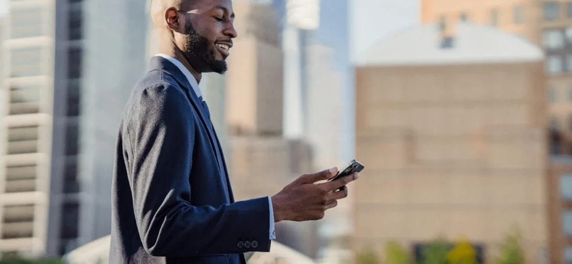 Un-homme-souriant-tenant-son-mobile-à-la-main