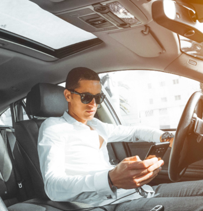 Un homme regardant son smartphone à l’arrêt dans sa voiture