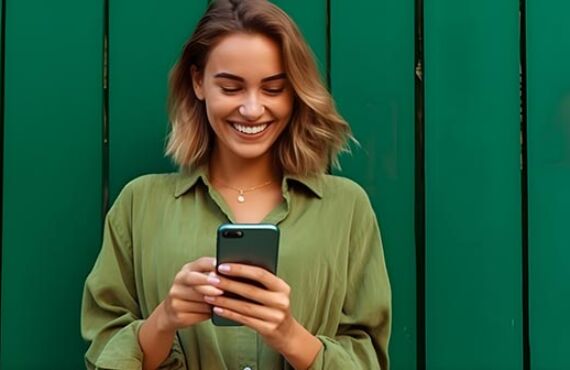 Portrait of a happy young woman using mobile phone over green ba